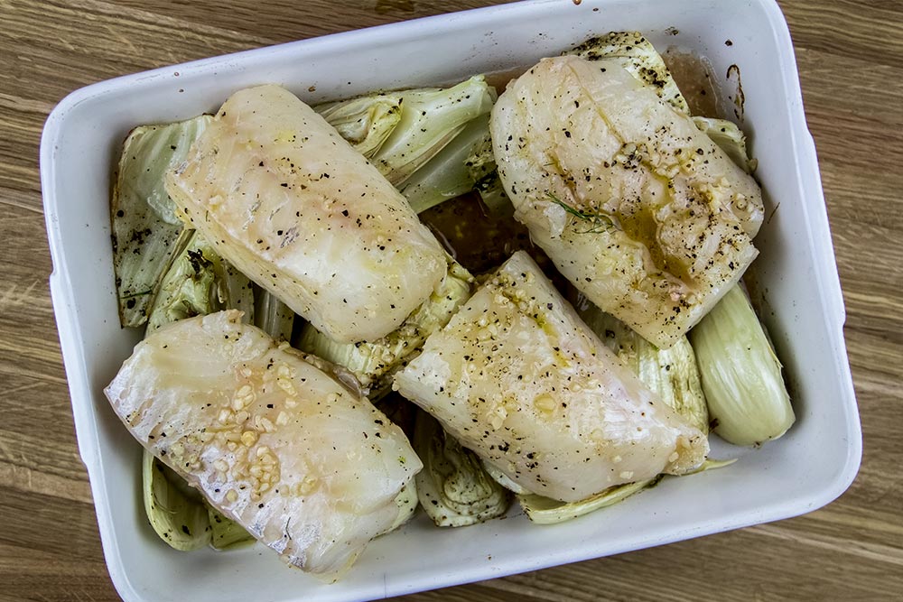 Raw Cod Arranged on Top of Fennel in Baking Tray