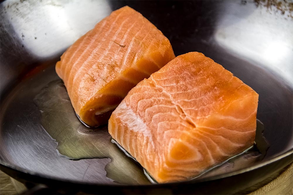 Raw Salmon Fillets in Stainless Steel Skillet