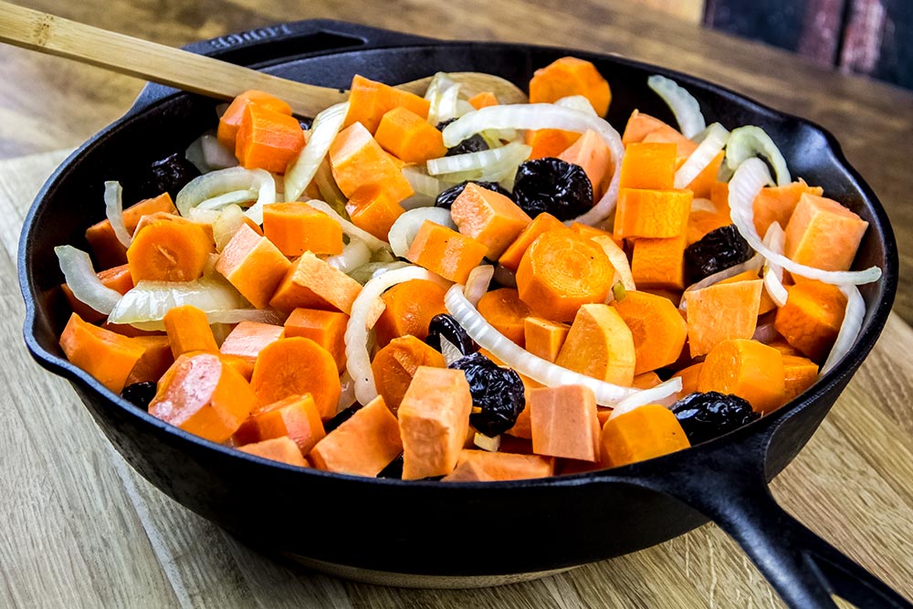 Adding Potato Pieces and Prunes to Cast Iron Skillet