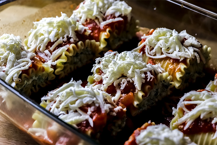 Shredded Mozzarella Cheese on Uncooked Lasagna Rolls